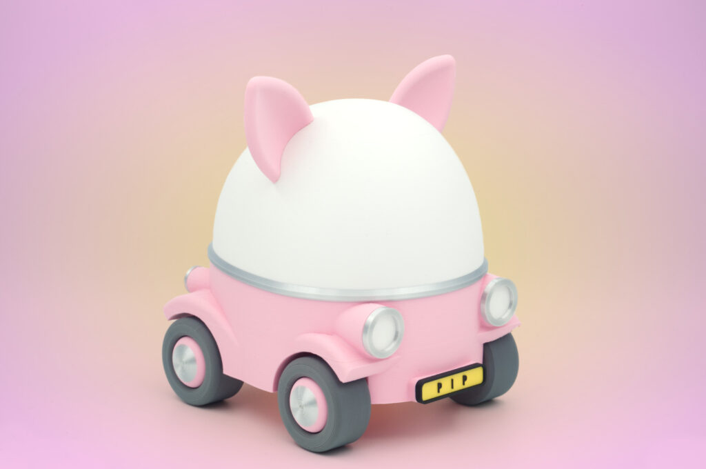 A cute My Little Cruiser toy car with animal ears in bright pink against a pink-to-yellow gradient background.